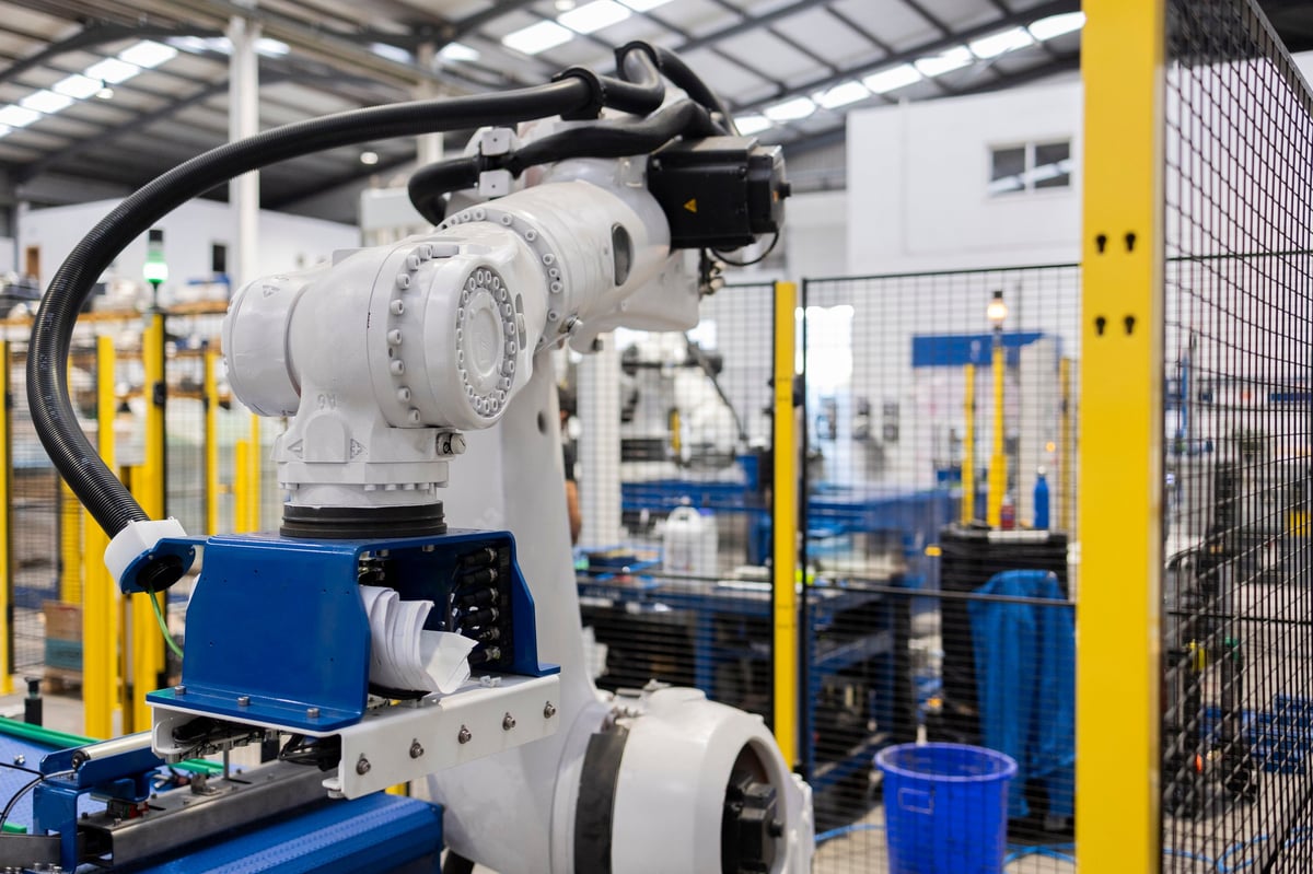 Robotic arm picking up material on an automated assembly line