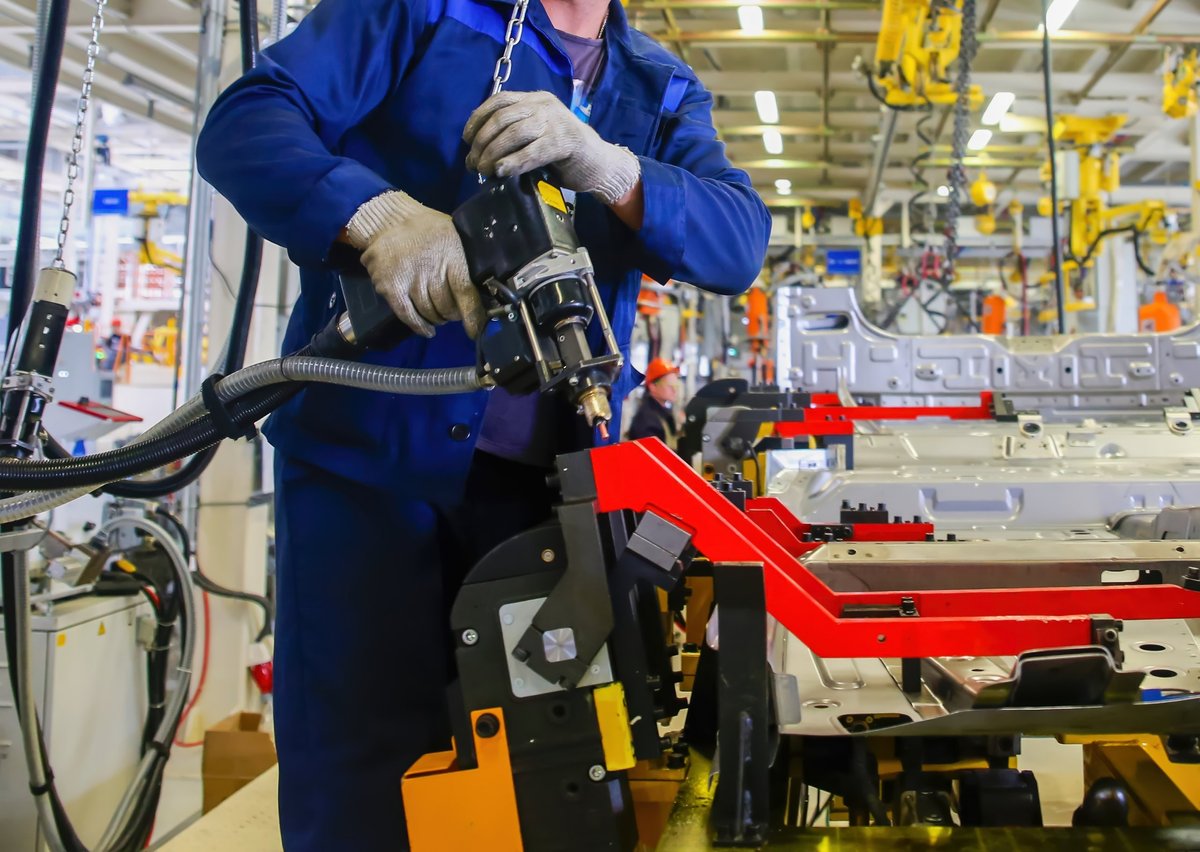 Technicians working on automotive parts with advanced tools in a production hall